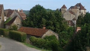 Ein ländliches Dorf mit Steinhäusern, einer Straße und einer Burg im Hintergrund.