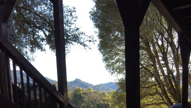 A covered outdoor area with a wooden staircase leading to a deck, a concrete floor, and a view of a natural landscape with trees and hills. - Luxury Lake Suite  9 Hole & Disc Golf with Hot Tub, Views, Large Patios. (Dos Rios)