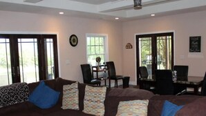 A living room with a brown sectional sofa, a ceiling fan, and a dining area with a table and chairs. - Luxury Lake Suite  9 Hole & Disc Golf with Hot Tub, Views, Large Patios. (Dos Rios)