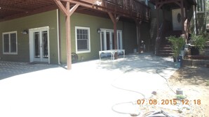 A wooden deck with a table and chairs, a covered porch, and a staircase leading to a second level. - Luxury Lake Suite  9 Hole & Disc Golf with Hot Tub, Views, Large Patios. (Dos Rios)