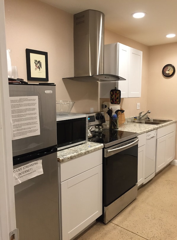 Fully equipped kitchen with stainless steel appliances, white cabinetry, and a range hood above the stove.