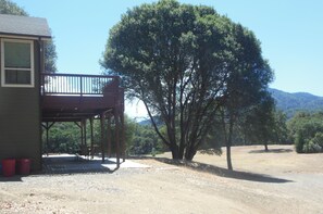 Situated in a natural setting, this cabin features a wooden deck and a covered outdoor seating area.