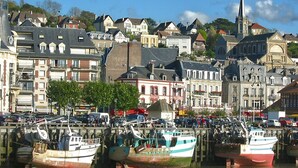 Un port où des bateaux sont amarrés, entouré de bâtiments historiques et d’un clocher d’église.