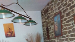 Ein Essbereich mit Steinwand, Holztisch, Stühlen und hängenden Lampen.