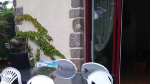 Eine Terrasse im Freien mit einem runden Tisch und vier weißen Plastikstühlen.
