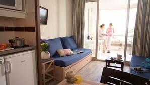 Un espacio habitable compacto con kitchenette, un sofá, una mesa de comedor y vistas al exterior.