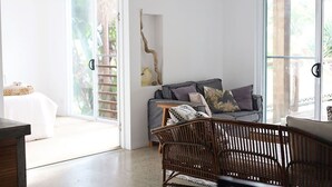 Un amplio espacio de estar con un sofá, una silla de mimbre y un sofá blanco.