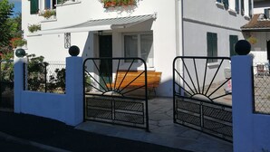 A two-story house with a white exterior, green shutters, and a balcony with flowers. - Apartment completely renovated in ground floor. (Saint-Jean-Pied-de-Port)