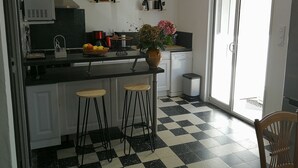 A kitchen with a black and white checkered floor, a central island with stools, a coffee maker, and a vase with flowers. - Apartment completely renovated in ground floor. (Saint-Jean-Pied-de-Port)