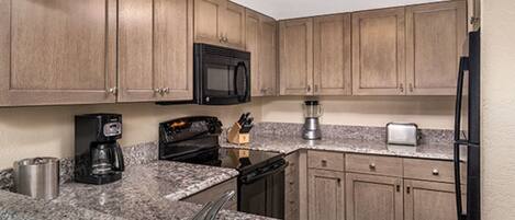 A kitchen with wooden cabinets, a microwave, a coffee maker, a toaster, and a refrigerator.