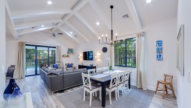 A spacious living area with a dining table and chairs, a sofa, and a ceiling fan. - New, modern pool villa in Naples Park / 15 min. walk to the beach (Naples)
