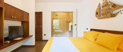 A bedroom with a bed, wooden cabinets, a television, and a ceiling fan.