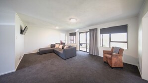 Un salón amplio con un sofá modular, un sillón de cuero y un ventanal que deja entrar mucha luz natural.