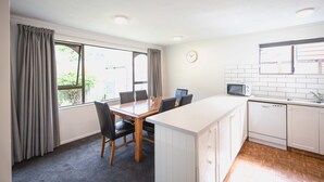 Una cocina compacta con comedor, armarios blancos, un microondas y un reloj en la pared.