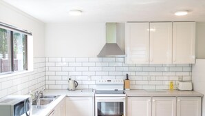 Una cocina moderna con armarios blancos, una campana extractora de acero inoxidable, horno empotrado y microondas.