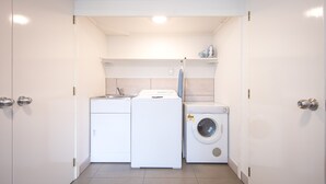 Un cuarto de lavandería con lavadora, secadora y estante con artículos de aseo.