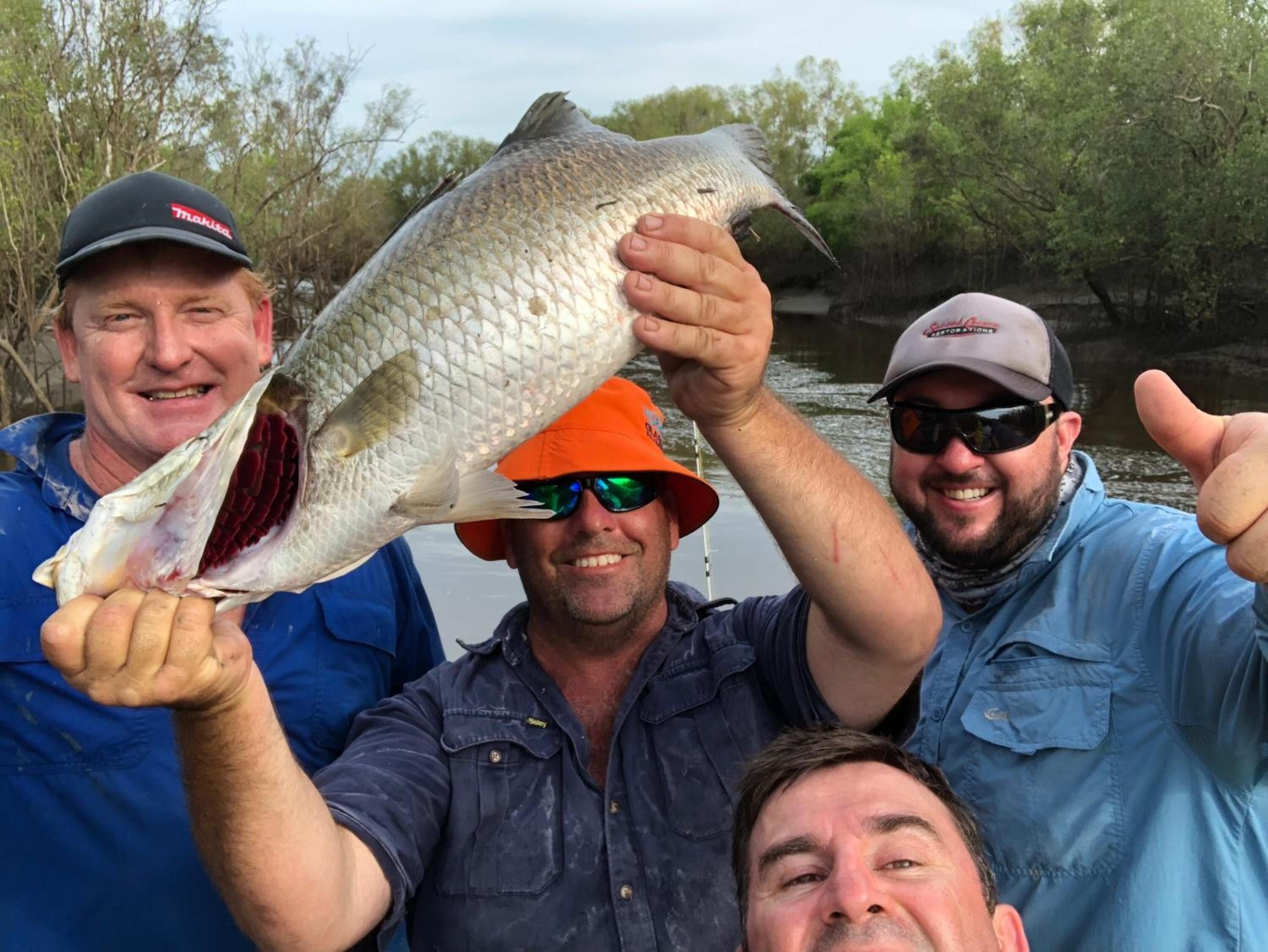 Three people holding a large fish, likely taken from a body of water.