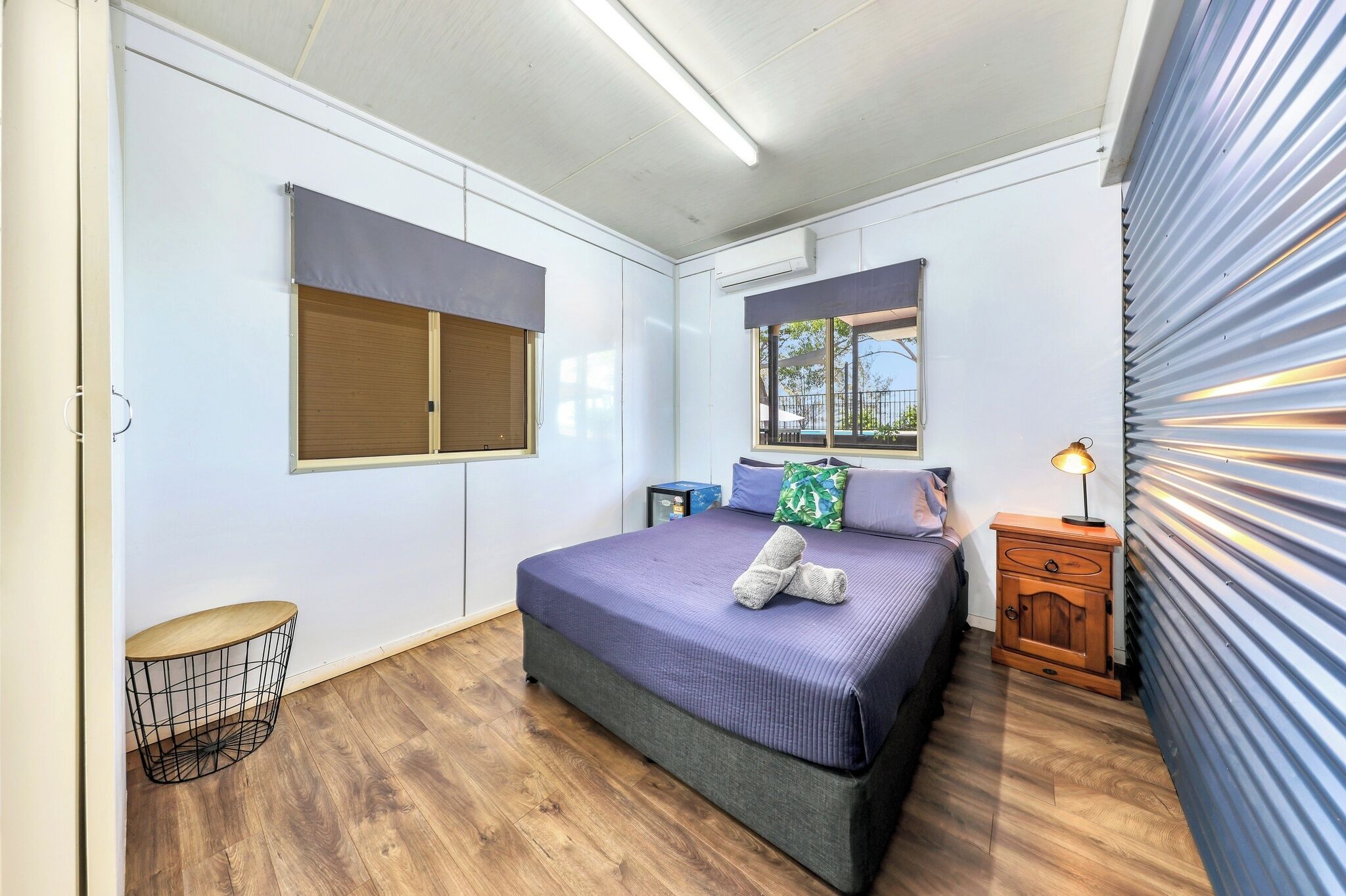 Un dormitorio con cama, mesita de noche y ventana.