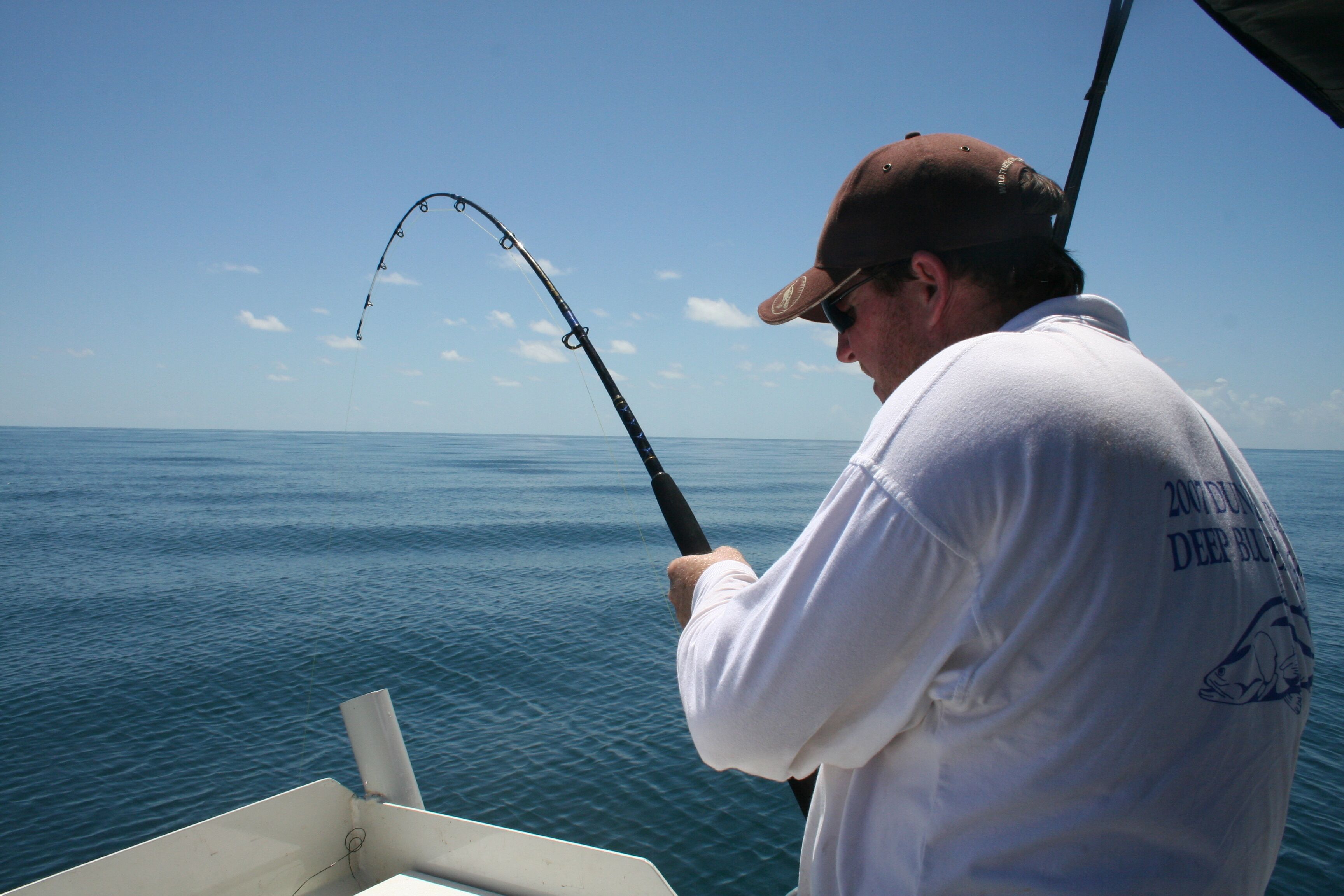 A person fishing on a boat with a clear view of the ocean.