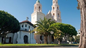 A church with two prominent towers and a smaller building with a balcony. - Cheerful Suite w/ Garden, Steps from Dolores Park (San Francisco)