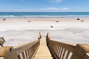Une promenade en bois qui mène à une plage d’où l’on a une vue dégagée sur l’océan.