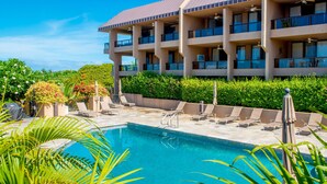 A hotel with a swimming pool surrounded by lounge chairs and greenery. - Kona Pacific A102, No stairs, Ocean View, Walk to town! Elevators, AC!! (Kailua Kona)