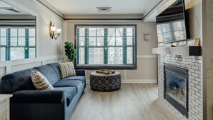 Una sala de estar moderna con chimenea, un ventanal con persianas, un sofá y una mesita de centro.