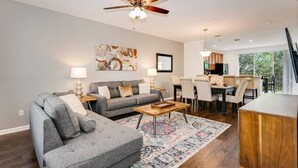 A living room with a gray sofa, a coffee table, and a dining area with chairs and a table.