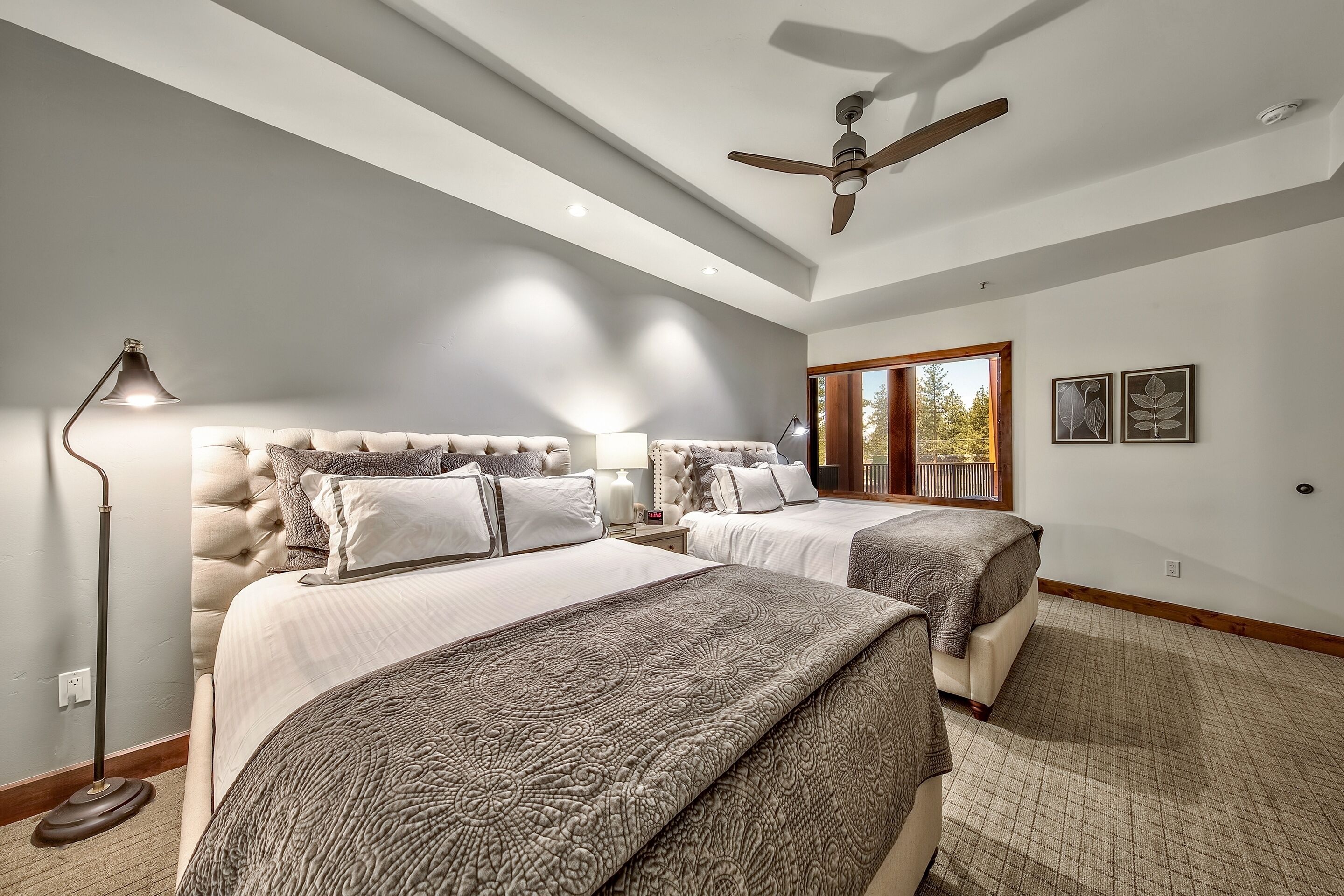 Ein Schlafzimmer mit zwei Betten, einem Deckenventilator und einem großen Fenster.