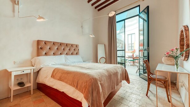 A modern bedroom with a large bed, bedside tables, a desk, and a chair.