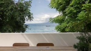 A terrace with a view of the sea and a boat, surrounded by trees. - Cabana (Gili Air)