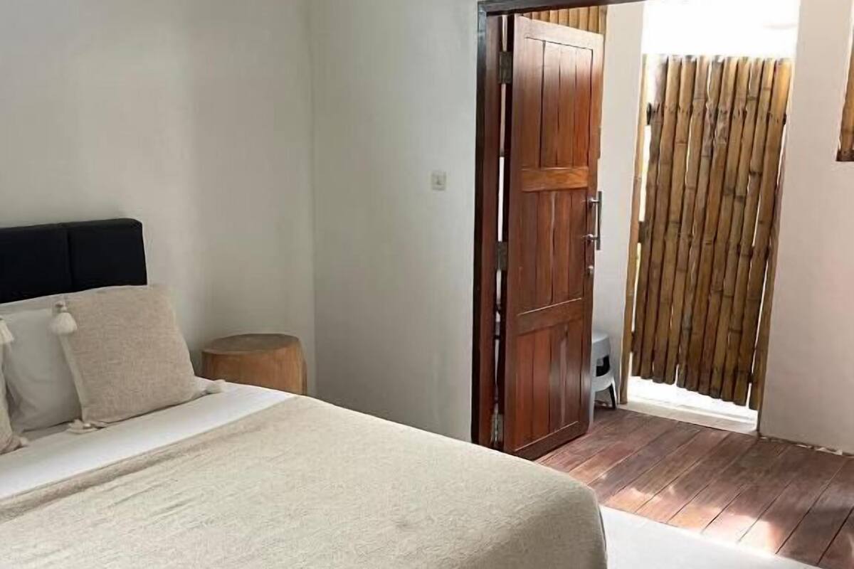 A bedroom with a bed, a wooden door, and a bamboo fence.