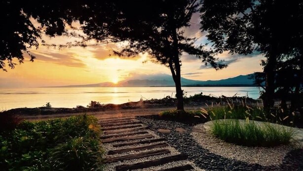 A pathway leading to a lake with a sunset in the background. - Cabana (Gili Air)