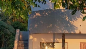 A modern building with a glass window, a wooden door, and a staircase leading to a balcony. - Cabana (Gili Air)