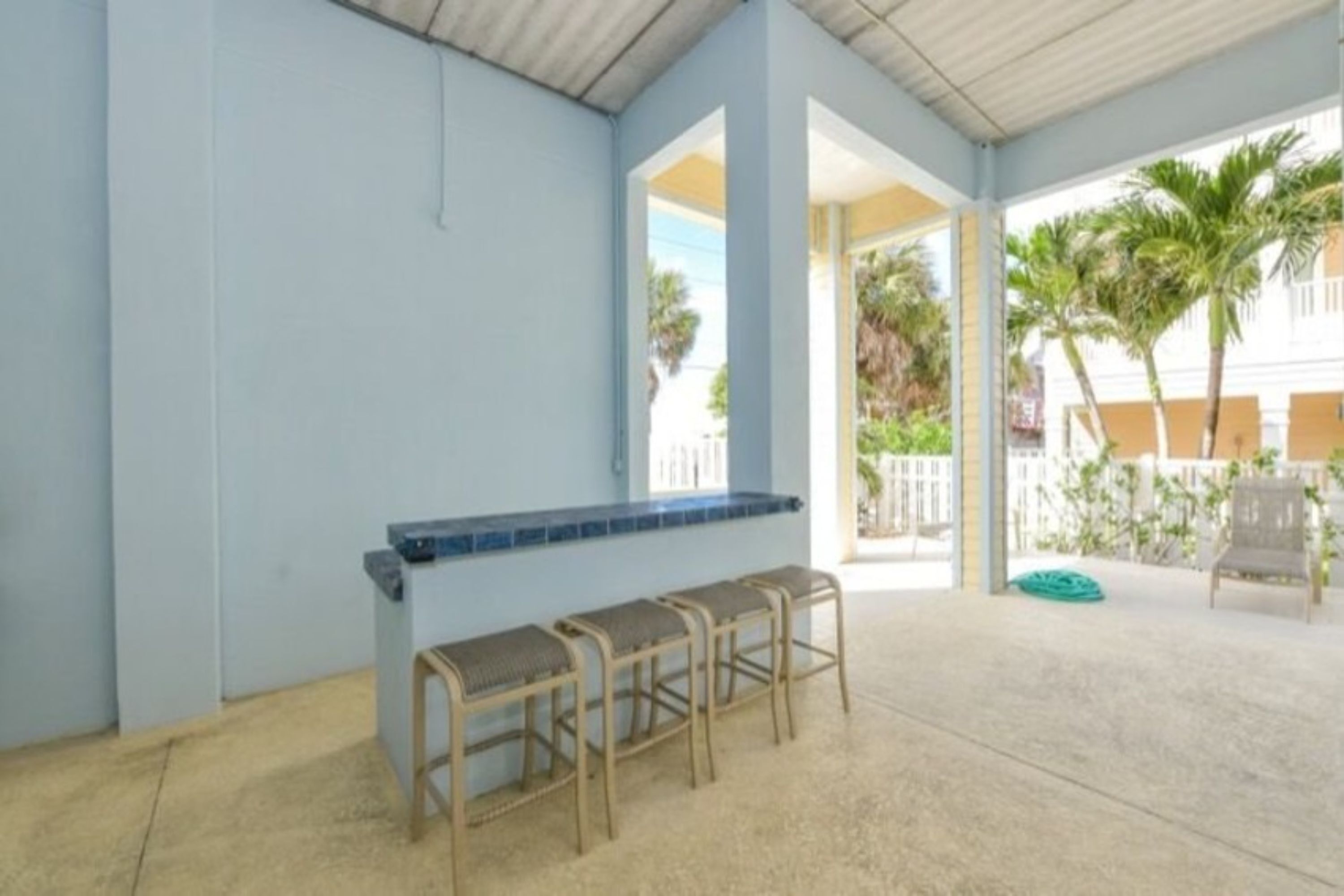 A covered outdoor area with a bar and three stools.