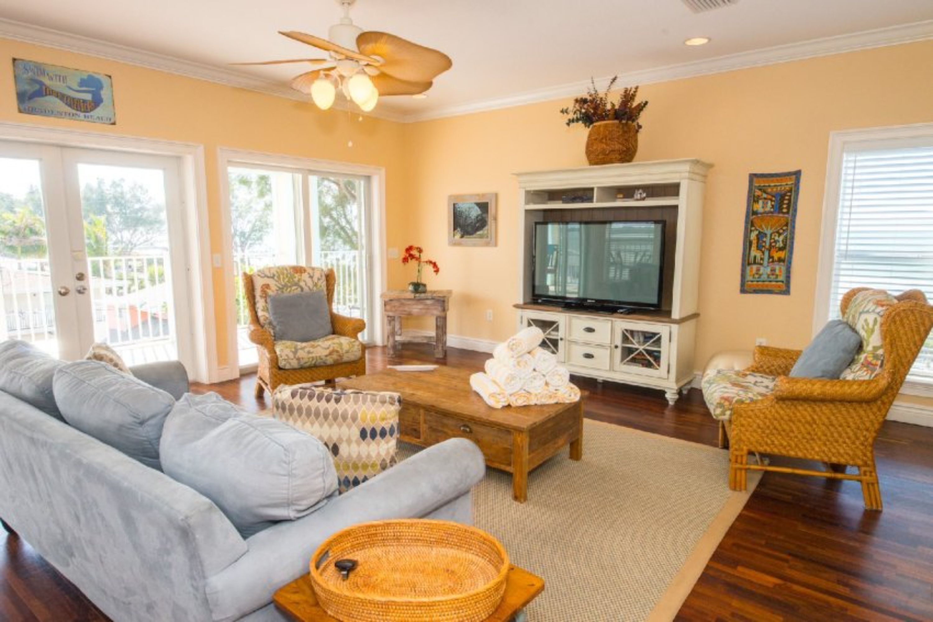 A living room with a sofa, chairs, a coffee table, a television, and a ceiling fan.