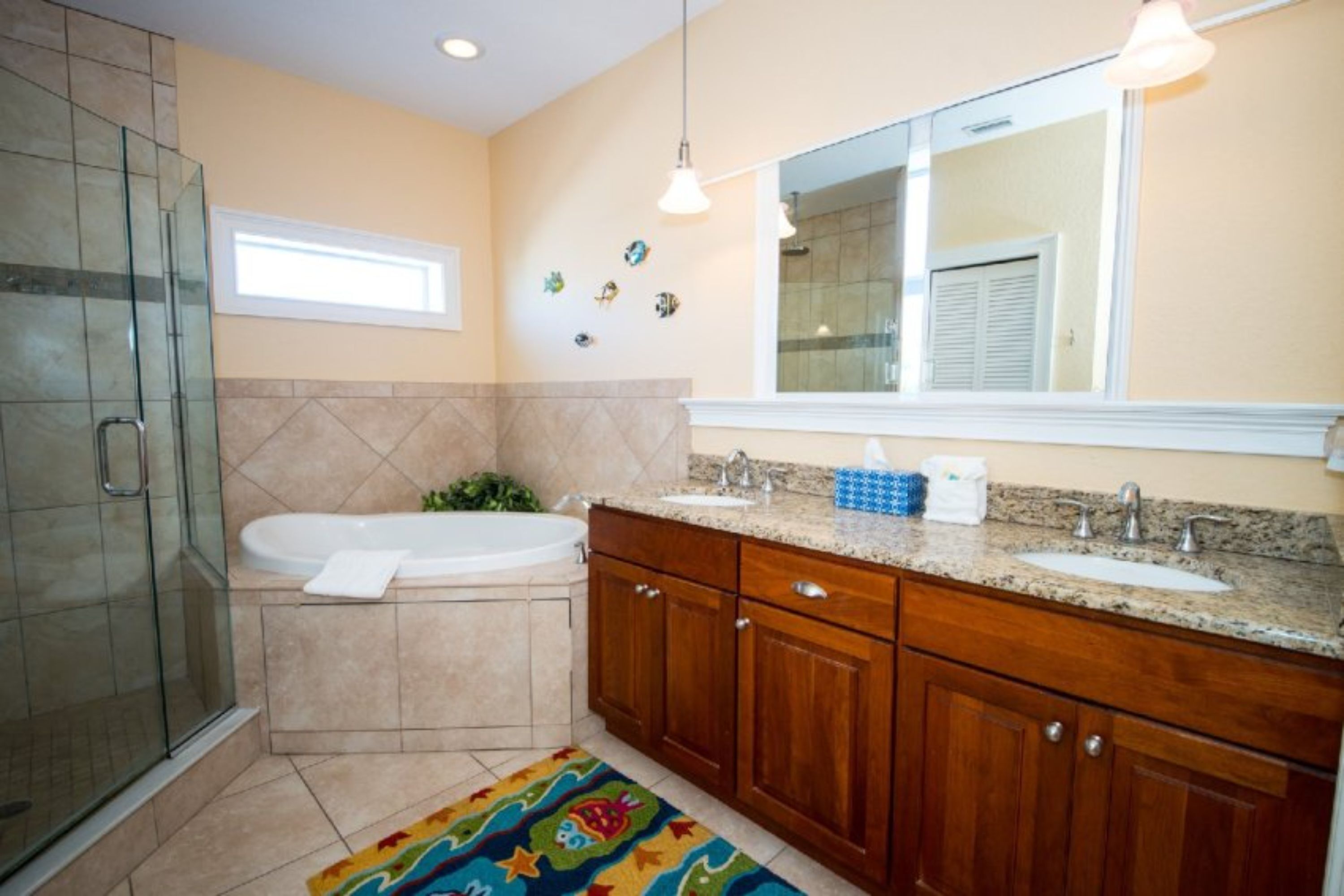 A bathroom with a glass shower enclosure, a bathtub, a vanity with a sink, and a mirror above the vanity.
