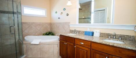 A bathroom with a glass shower enclosure, a bathtub, a vanity with a sink, and a mirror above the vanity.