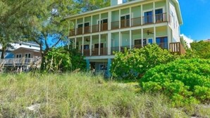A multi-story building with balconies, surrounded by greenery. - 2903 Avenue F 3 Bedroom Home by RedAwning (Holmes Beach)