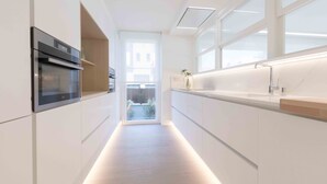 A modern kitchen with built-in appliances, a large window, and a view of the outside. - Brunet II | The Rentals Collection (San Sebastián)