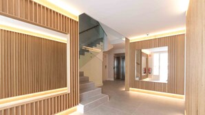 A modern interior with a staircase, wooden paneling, and a fire extinguisher. - Brunet II | The Rentals Collection (San Sebastián)