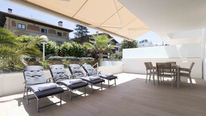 A rooftop terrace with sun loungers, a dining table, and a large canopy providing shade. - Brunet II | The Rentals Collection (San Sebastián)