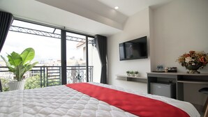 A hotel room with a large bed, a TV mounted on the wall, a desk with a computer, and a balcony with a plant. - Bin Bin Hotel 7 - Near Ton Duc Thang University (Ho Chi Minh City)