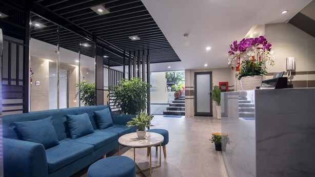 A modern hotel lobby with a blue sofa, a round table, and potted plants. - Bin Bin Hotel 7 - Near Ton Duc Thang University (Ho Chi Minh City)