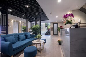 Un moderno vestíbulo de hotel con un sofá azul, una mesa redonda y plantas en macetas.