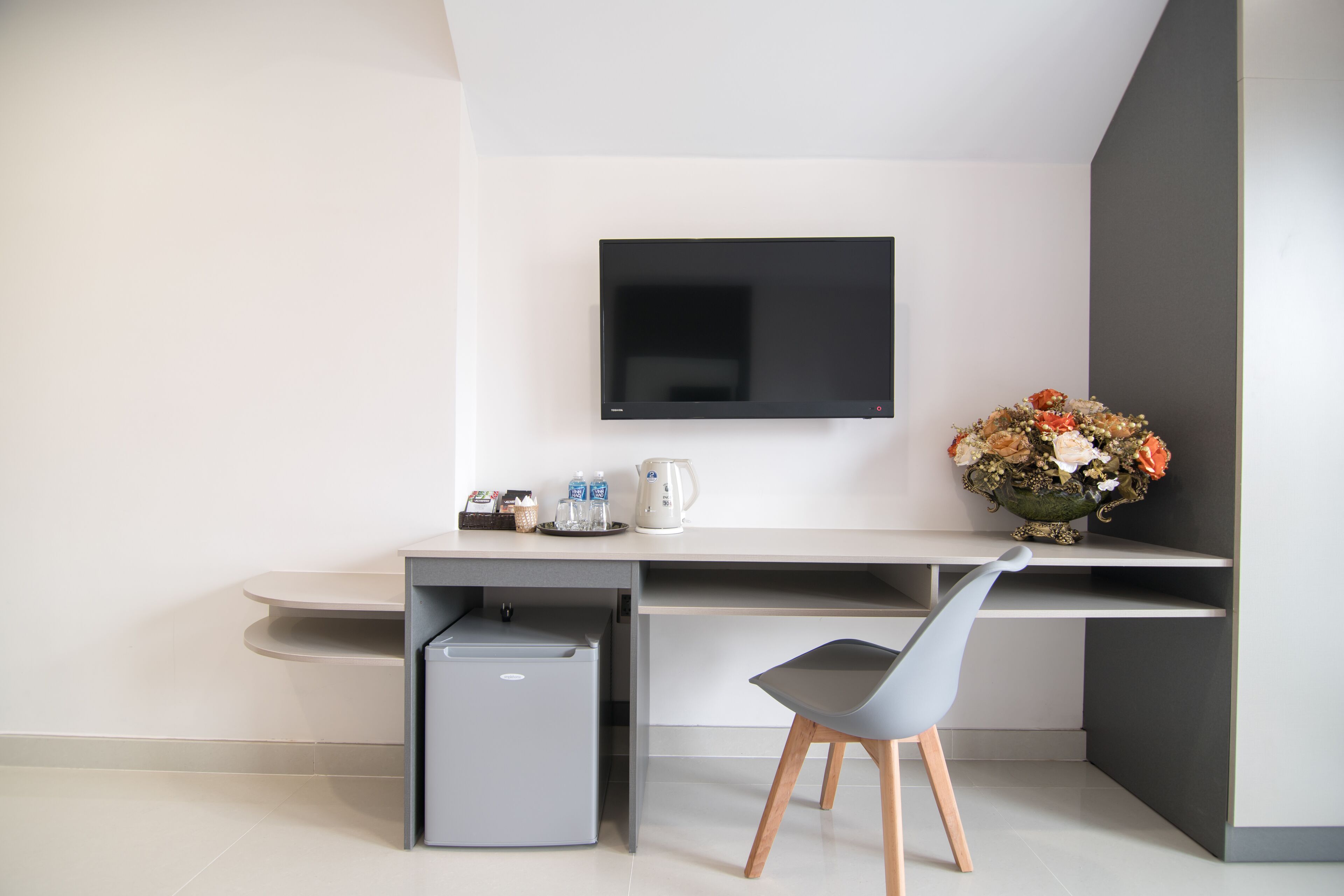 A modern kitchen with a built-in refrigerator, a sink, and a countertop with a kettle and a vase of flowers.