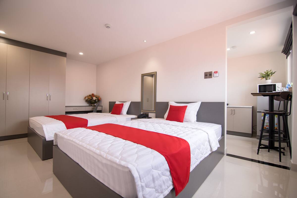 A hotel room with two beds, a desk, and a chair.