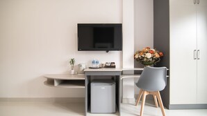 A modern kitchen with a built-in refrigerator, a flat-screen TV mounted above the counter, and a grey chair. - Bin Bin Hotel 7 - Near Ton Duc Thang University (Ho Chi Minh City)