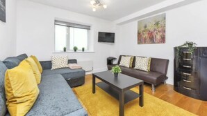 A modern living room with a grey sofa, a brown sofa, and a coffee table. There is a window with blinds and a painting on the wall. - Little Corner of Bliss in BustlingLondon (London)