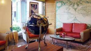 A room with a globe on a stand, a red sofa, a wooden coffee table, and a world map on the wall. - Gueylin Hotel (Taoyuan City)